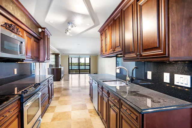 a kitchen with granite countertop a stove top oven a sink dishwasher a dining table and chairs with wooden floor