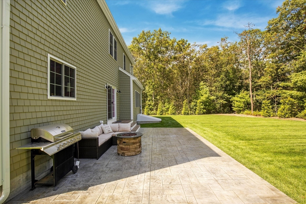 23 Pimlico Pond Road Mashpee, MA 02649 - Photo 39 of 42 a backyard of a house with large trees and outdoor seating