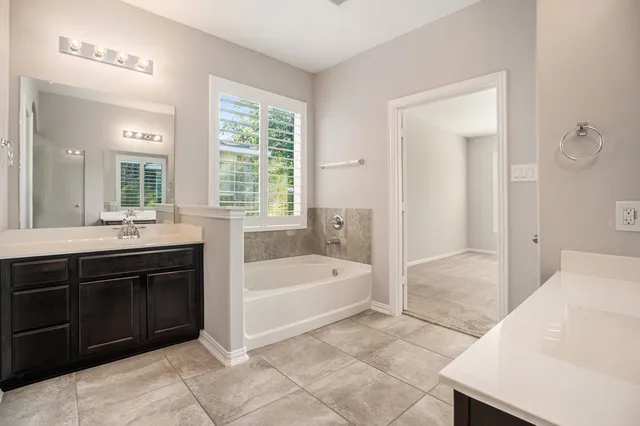 a spacious bathroom with a tub sink and mirror