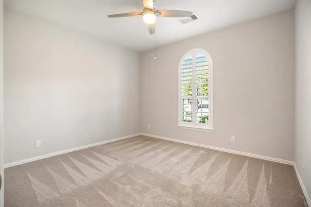 an empty room with windows and chandelier fan