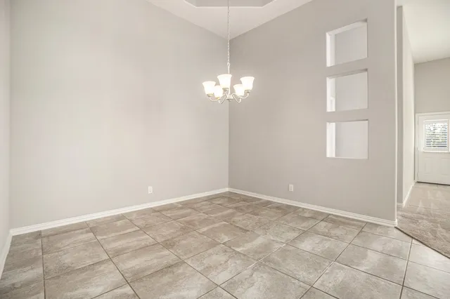 an empty room with windows and chandelier fan