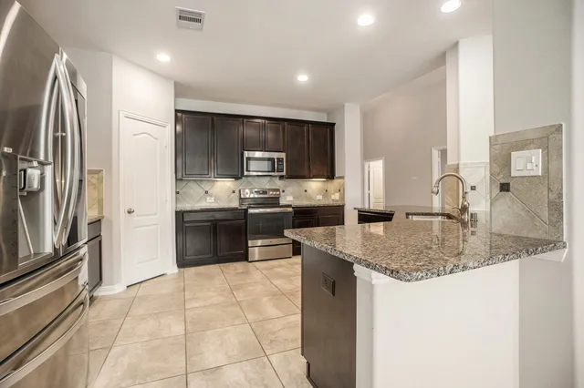 a kitchen with stainless steel appliances granite countertop a sink stove and refrigerator