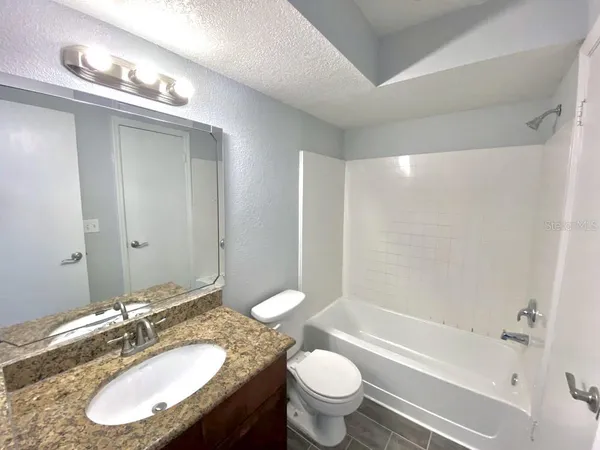 a bathroom with a granite countertop sink toilet a large mirror a bathtub and shower