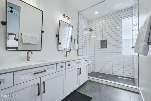 a bathroom with a double vanity sink a mirror and a shower