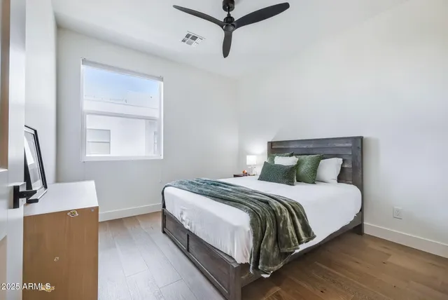 a bedroom with a bed lamp on desk and a window