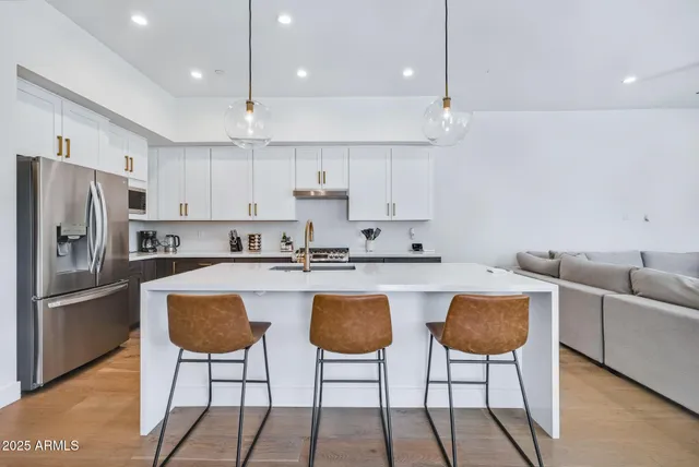 a kitchen with stainless steel appliances granite countertop a refrigerator a stove a sink and chairs