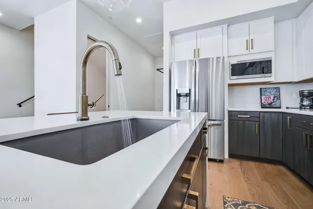 a kitchen with stainless steel appliances granite countertop a sink a stove and refrigerator