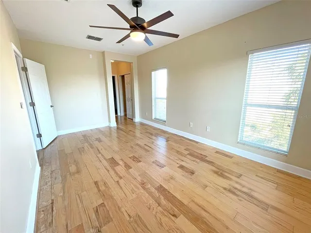 a view of empty room with wooden floor and fan