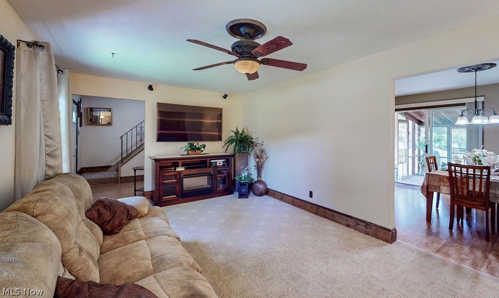 Living room with carpet flooring and ceiling fan with notable chandelier