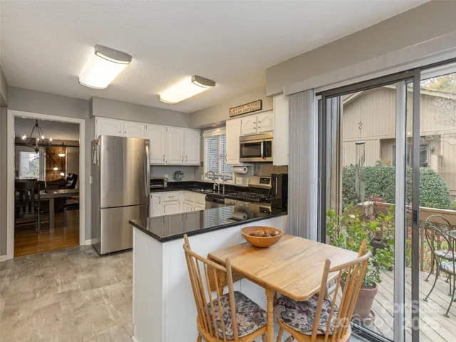 a kitchen with a refrigerator a stove a microwave oven with a dining table and chairs