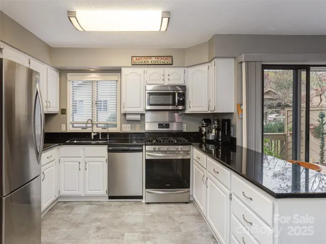 a kitchen with stainless steel appliances granite countertop a stove top oven a sink and a refrigerator
