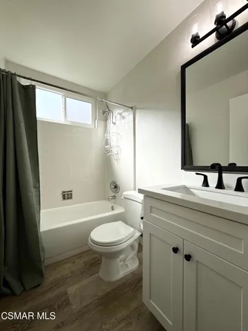 a bathroom with a sink a toilet a mirror a bathtub and shower