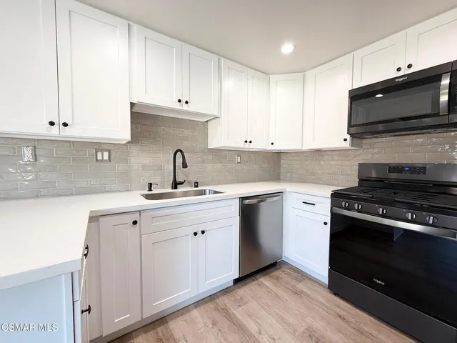 a kitchen with stainless steel appliances granite countertop a sink a stove a microwave and cabinets