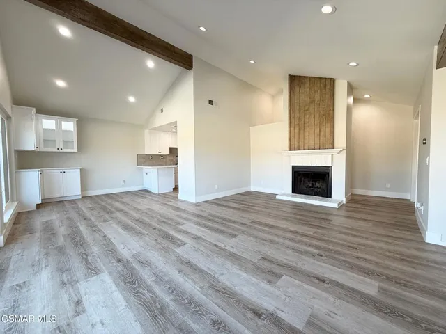 a view of empty room with wooden floor and kitchen