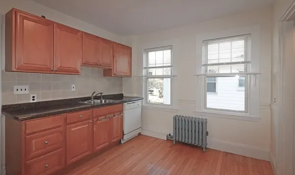 a kitchen with granite countertop wooden floors a sink and dishwasher with wooden floor