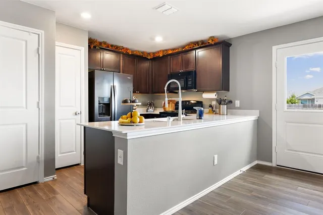 a kitchen with stainless steel appliances a refrigerator and a wooden floor