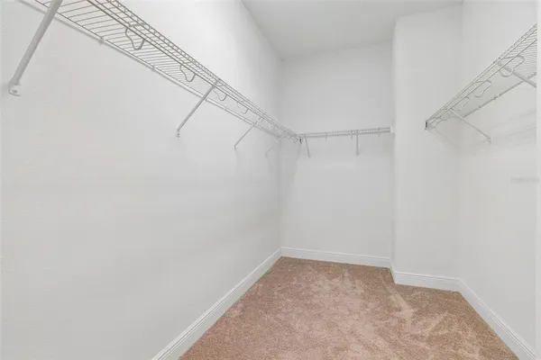 an empty room with chandelier fan and windows
