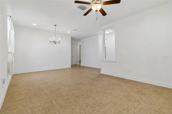 an empty room with chandelier fan and windows