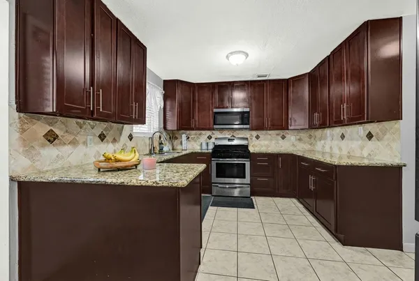 a kitchen with stainless steel appliances granite countertop wooden cabinets a stove top oven a sink and dishwasher