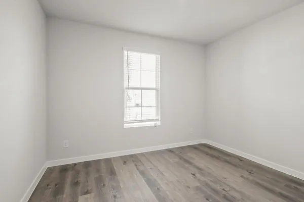 an empty room with wooden floor and window