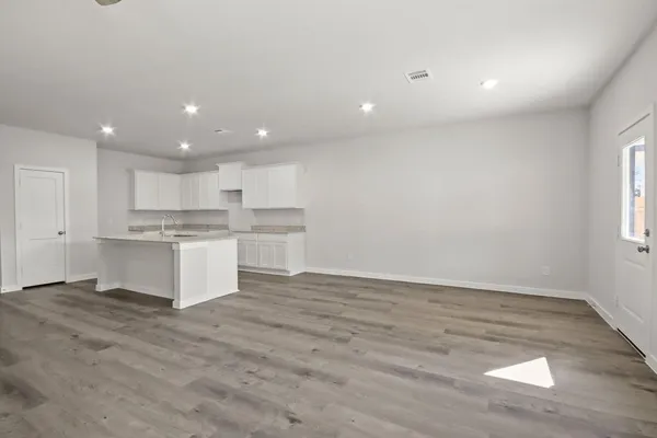 a large white kitchen with kitchen island a sink wooden floor and a refrigerator