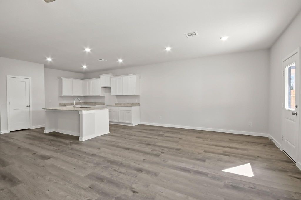 496 Shoreview Drive Conroe, TX 77303 - Photo 5 of 20 a large white kitchen with kitchen island a sink wooden floor and a refrigerator