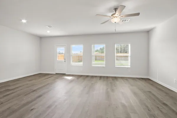 a view of an empty room with a window and wooden floor