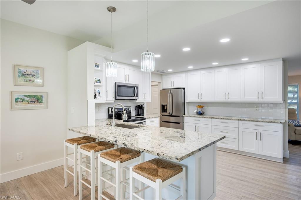 1410 Curlew Avenue Naples, FL 34102 - Photo 12 of 44 a kitchen with stainless steel appliances granite countertop a stove top oven a sink dishwasher a dining table and chairs with wooden floor
