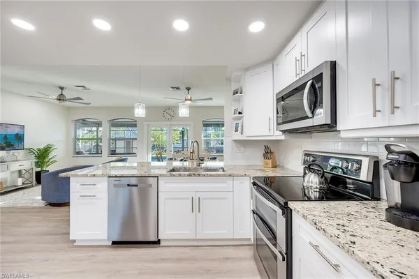 a kitchen with stainless steel appliances granite countertop a stove top oven a sink dishwasher a dining table and chairs with wooden floor