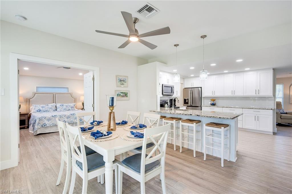 1410 Curlew Avenue Naples, FL 34102 - Photo 8 of 44 a kitchen with stainless steel appliances kitchen island granite countertop a table chairs and a refrigerator