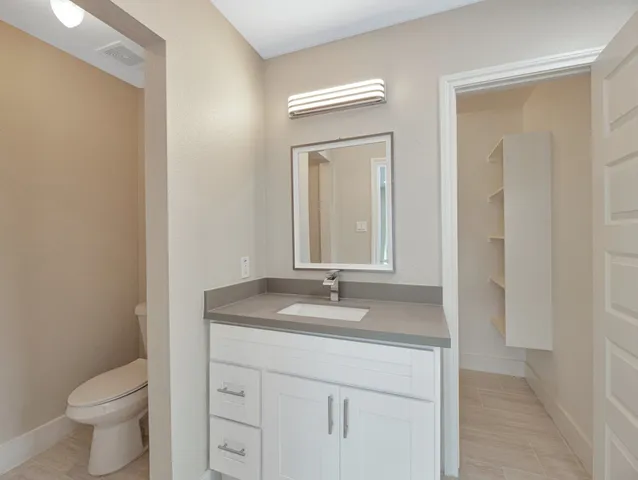 a bathroom with a granite countertop sink a toilet and a mirror
