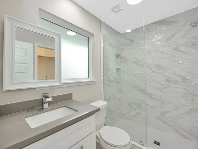 a bathroom with a sink a toilet and shower