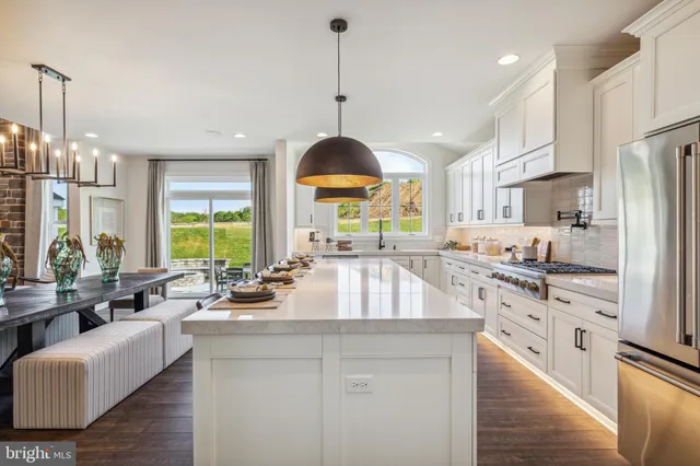 a kitchen with stainless steel appliances granite countertop a stove a sink a center island a refrigerator and a cabinets