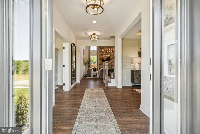 a hallway with wooden floor chandelier and living room
