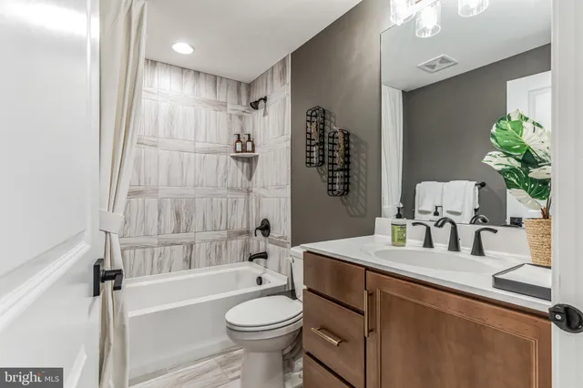 a bathroom with a bathtub shower sink vanity mirror and toilet