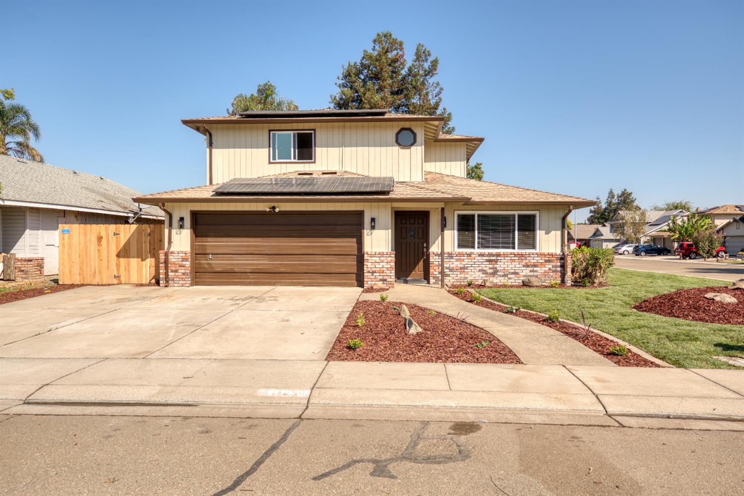1621 Davis Street Ripon, CA 95366 - Photo 6 of 43 traditional-style home with solar panels, concrete driveway, a garage, a gate, and brick siding