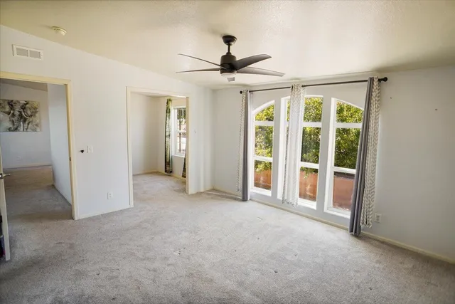 an empty room with windows and a ceiling fan
