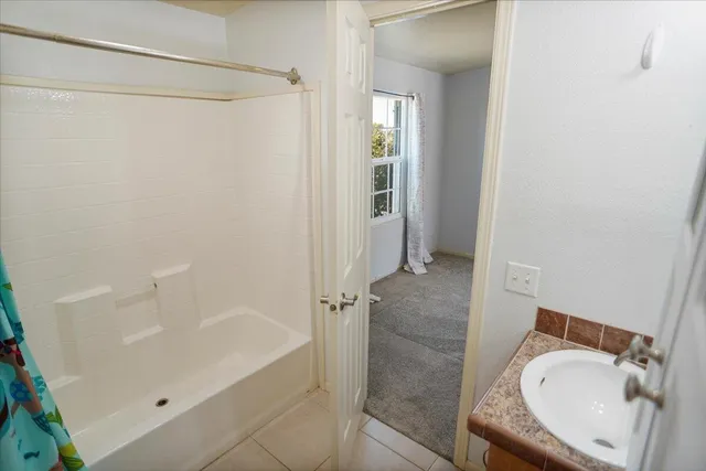 a bathroom with a tub shower and a sink