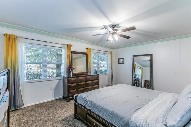 a bedroom with a large bed large window with table and chair