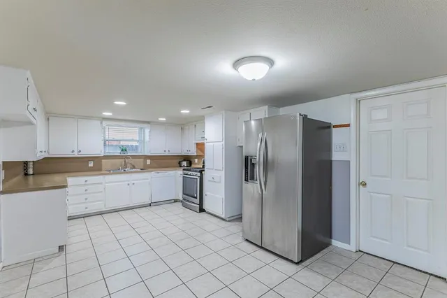 a kitchen with a refrigerator and white cabinets