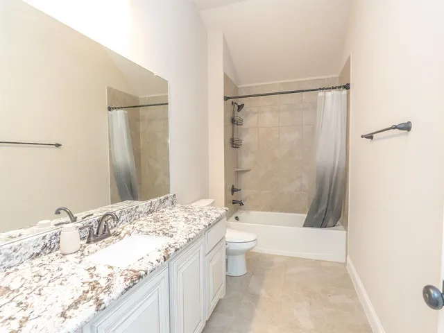 a bathroom with a granite countertop sink toilet and shower
