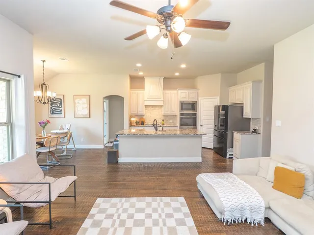 a living room with couches and kitchen view with wooden floor