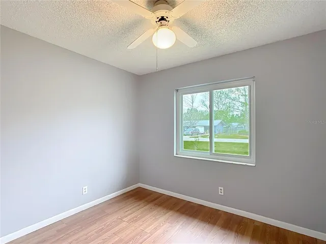 an empty room with a window and a fan