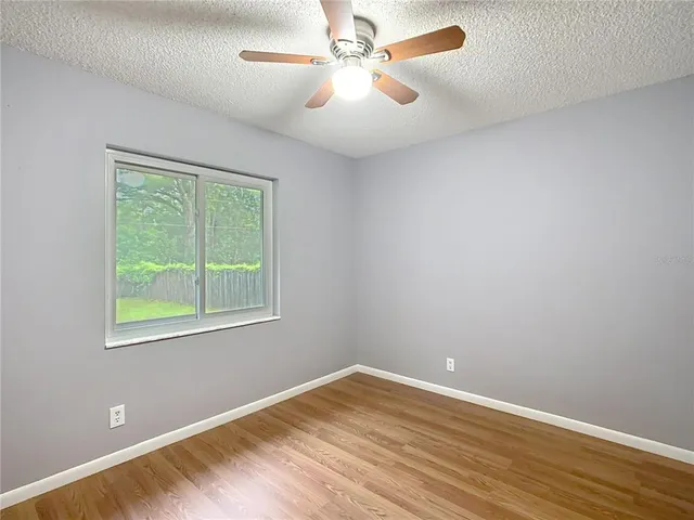 an empty room with a window and a fan