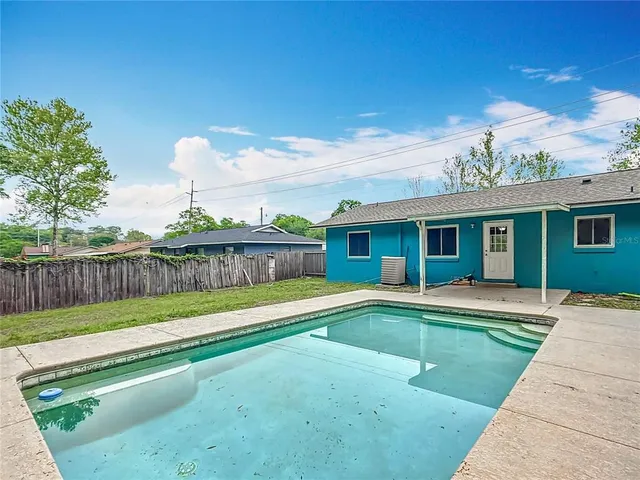a swimming pool with a yard and wooden fence