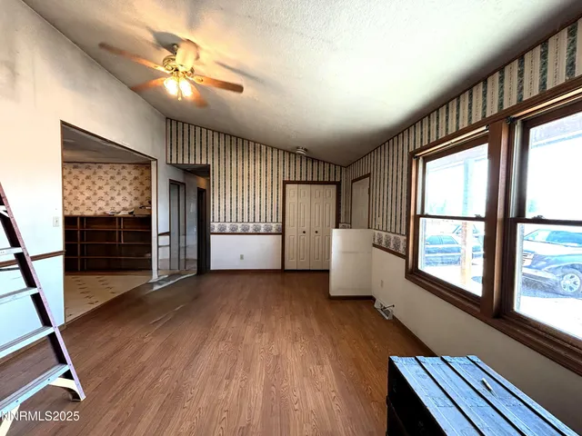 a view of an empty room with a window and wooden floor