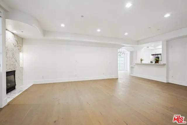 a view of empty room with kitchen and fireplace