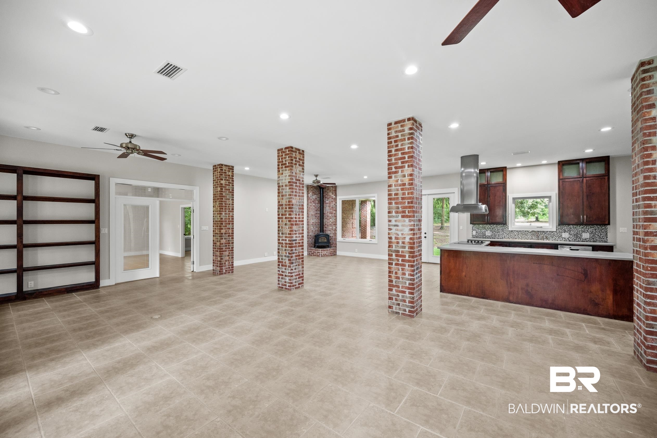 15031 Timber Ridge Drive Loxley, AL 36551 - Photo 9 of 43 Interior space featuring a wood stove, kitchen peninsula, backsplash, ceiling fan, and island range hood