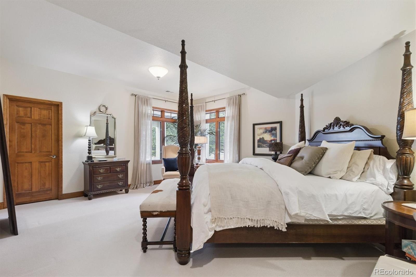 8061 Sugar Loaf Road Larkspur, CO 80118 - Photo 37 of 48 a bedroom with a large bed and wooden floor