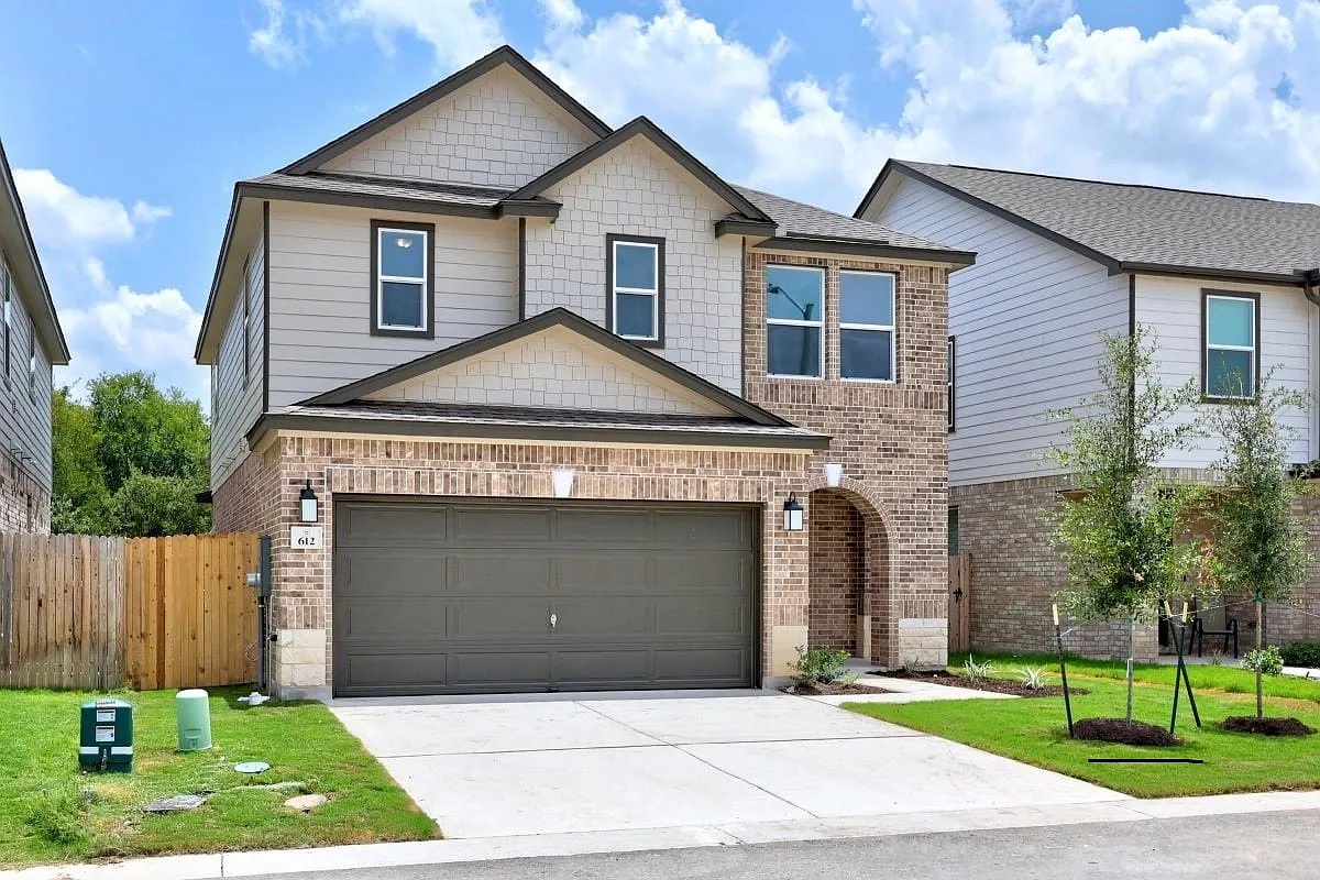 612 St Cindy's Way Pflugerville, TX 78660 - Photo 4 of 6 A striking modern home showcasing a blend of brick and siding, with an attached garage and well-maintained front yard.